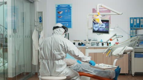 Dentist-and-assistant-in-coverall-examining-mouth-of-patient