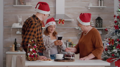 Grandparents-with-grandchild-wearing-santa-hat-greeting-remote-friends-during-online-videocall