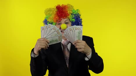 Elderly-clown-businesswoman-freelancer-boss-dancing-with-money-cash-banknotes