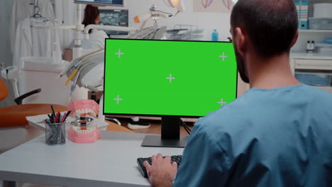 Man-looking-at-computer-with-horizontal-green-screen