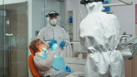 Doctor-with-protective-mask-doing-hygienic-cleaning-of-teeth