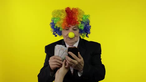Senior-clown-businesswoman-entrepreneur-loses-money-on-online-smartphone-working