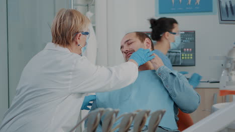 Dentista-Senior-Examinando-A-Un-Paciente-Con-Dolor-De-Muelas-Grave