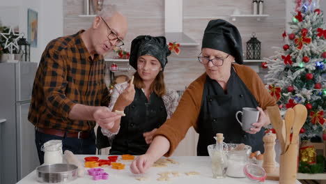 Grandparents-teaching-granddaughter-how-prepare-gingerbread-dessert-shape