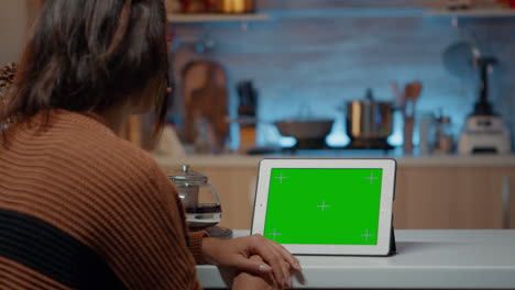 Festive-woman-looking-at-green-screen-display-on-tablet