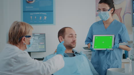 Paciente-Y-Equipo-De-Odontología-Mirando-Tableta-Con-Pantalla-Verde