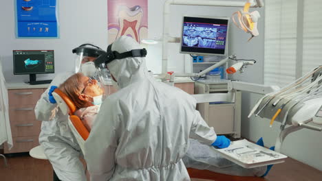 Nurse-and-doctor-in-protection-suit-working-in-dental-unit