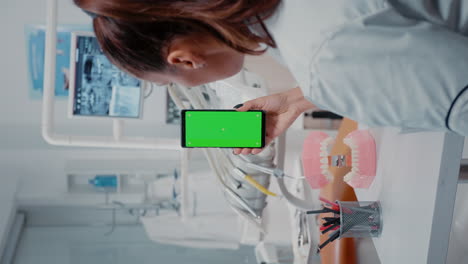 Vertical-video:-Woman-vertically-holding-mobile-phone-with-green-screen