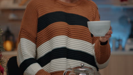 Close-up-of-young-adult-holding-cup-of-tea-in-kitchen