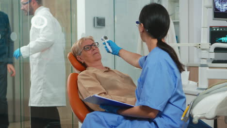Enfermera-Midiendo-La-Temperatura-De-La-Anciana-Antes-Del-Examen-Dental