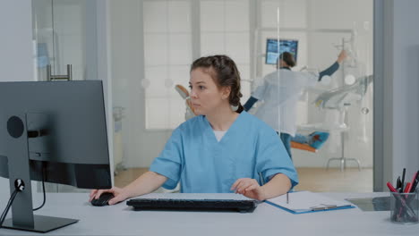 Zahnmedizinische-Krankenschwester-Sitzt-Am-Schreibtisch-Und-Tippt-Auf-Der-Computertastatur