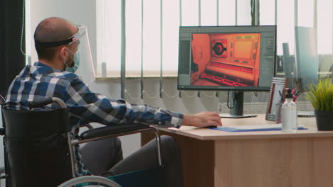 Handicapped-game-developer-in-wheelchair-with-mask-working