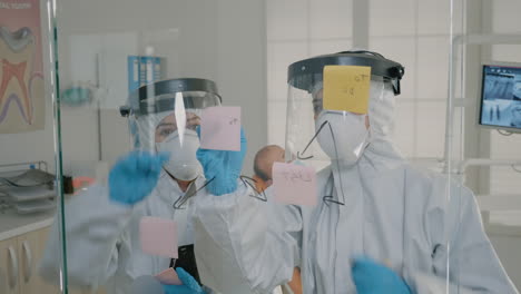 Orthodontists-in-ppe-suits-making-diagram-with-sticky-notes