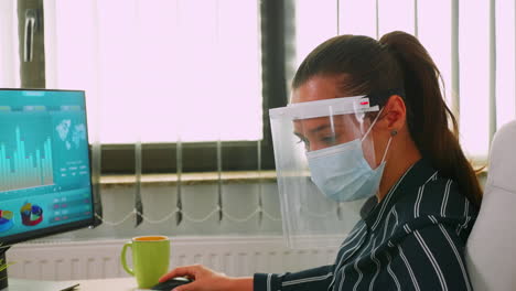 Close-up-of-businesswoman-wearing-protection-mask-on-desk-office