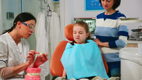 Zahnarzt-Erklärt-Mädchen-Die-Vorgehensweise-Der-Extraktion-Anhand-Eines-Zahnmodells