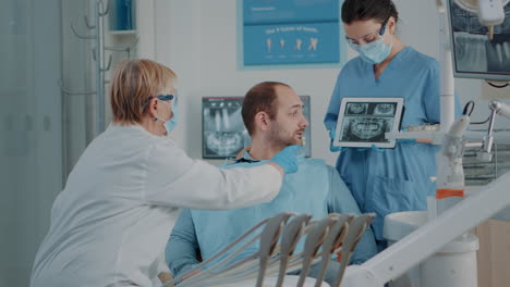 Dentista-Y-Enfermera-Mostrando-Resultados-De-Rayos-X-A-Un-Paciente-Con-Dolor-De-Muelas