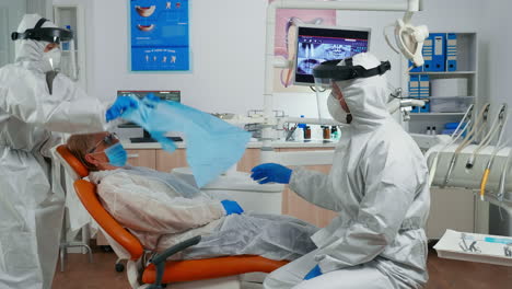 Assistant-in-protective-equipment-putting-dental-bib-to-patient