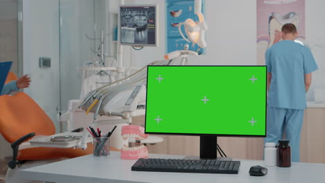 Monitor-Mit-Grünem-Bildschirm-Auf-Dem-Schreibtisch-In-Der-Zahnarztpraxis