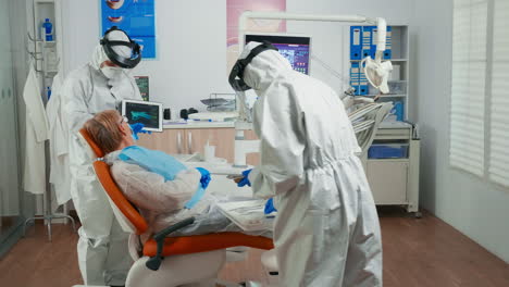 Zahnarzt-In-Schutzausrüstung,-Der-Röntgenaufnahmen-Mit-Einem-Tablet-überprüft