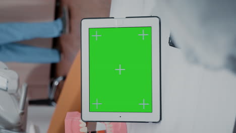 Vertikales-Video:-Nahaufnahme-Eines-Zahnarztes-Mit-Grünem-Bildschirm-Auf-Einem-Tablet