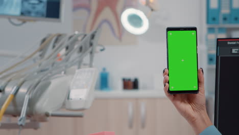 Close-up-of-dentist-holding-smartphone-with-green-screen