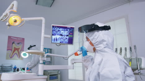 Patient-pov-looking-at-dentist-in-ppe-suit-showing-teeth-x-ray