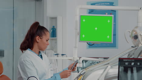 Dentist-analyzing-horizontal-green-screen-on-monitor