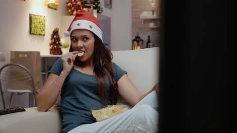 Woman-wearing-santa-hat-and-looking-at-movie-on-TV