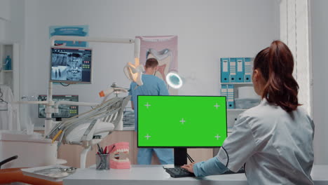 Dentist-using-green-screen-on-monitor-and-talking-to-man-assistant