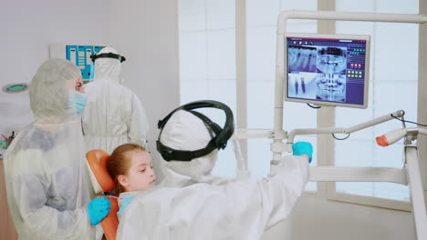 Stomatologist-in-coverall-explaining-dental-problem-using-digital-monitor