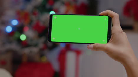 Close-up-of-hand-holding-horizontal-green-screen-on-smartphone