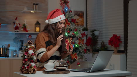 Adult-holding-present-on-video-call-in-festive-kitchen