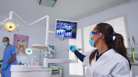 Doctor-En-Odontología-Hablando-De-Cirugía-Mostrando-Rayos-X-En-El-Monitor