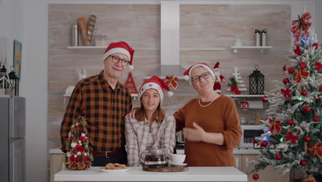 Pov-of-family-wearing-santa-hats-greeting-friends-during-online-videcall-meeting-conference