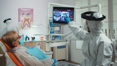 Doctor-with-face-shield-pointing-on-stomatological-monitor