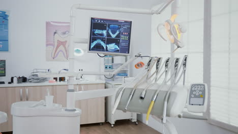 Revealing-shot-of-orthodontist-chair-with-nobody-in,-dental-x-ray-images-on-display