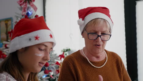 Portrait-of-grandmother-with-granddaughter-wearing-santa-hats