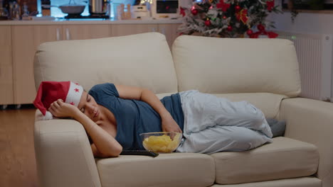 Sleepy-woman-wearing-santa-hat-and-resting-on-couch
