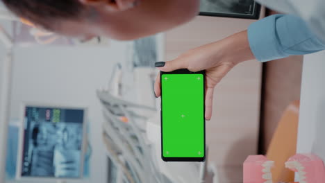 Vertical-video:-Woman-holding-smartphone-with-horizontal-green-screen