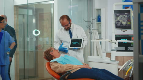 Doctor-showing-x-ray-of-teeth-to-patient-using-tablet