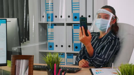 Woman-with-mask-talking-on-videocall-with-remotely-coworker