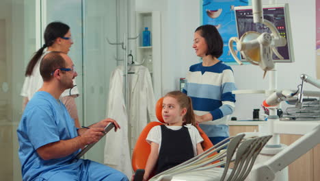 Hombre-Amigable-Dentista-Asistente-Interrogando-A-Niño-Paciente