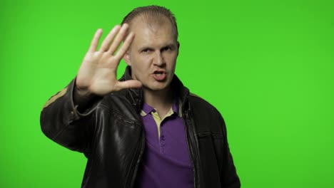 Rocker-man-showing-stop-gesture-with-hands.-No,-never,-disliking-and-rejecting-sign.-Chroma-key