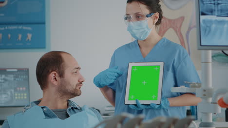 Stomatology-nurse-vertically-holding-tablet-with-green-screen