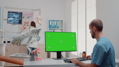 Man-working-with-keyboard-and-computer-with-green-screen