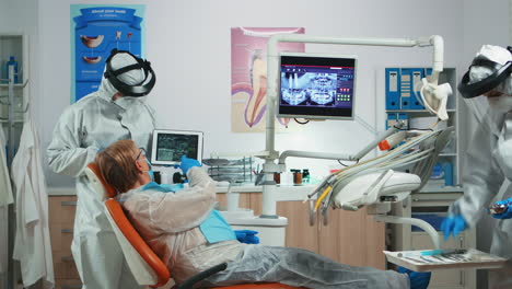 Dentista-En-Mono-Examinando-La-Imagen-De-Rayos-X-En-La-Tableta