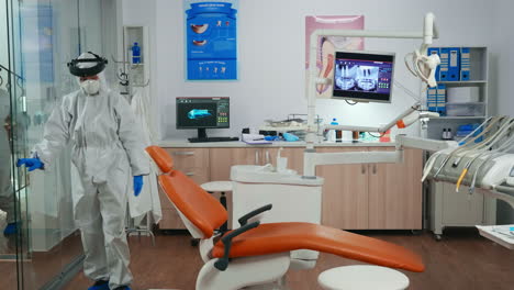 Nurse-with-protection-suit-inviting-next-patient-in-stomatology-room