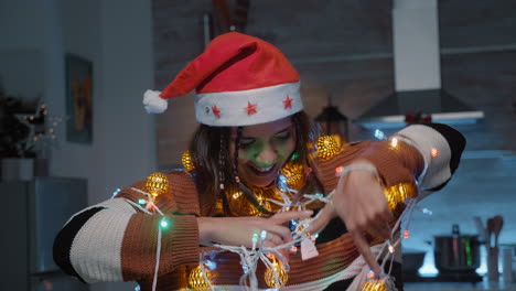 Festive-woman-with-santa-hat-trying-to-untangle-lights