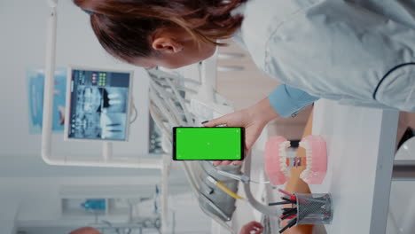 Vertical-video:-Woman-vertically-holding-mobile-phone-with-green-screen