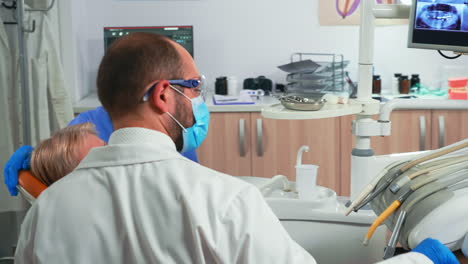 Dentista-Y-Asistente-Trabajan-Con-Un-Paciente-En-Una-Clínica-Dental-Moderna